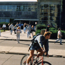 1990s man riding bike outside Union by students walking
