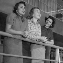 Three 1950s women leaning on railing